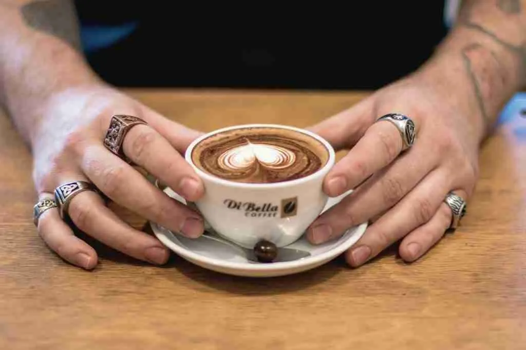 A photo of a coffee mug with a love heart shape made in the coffee.