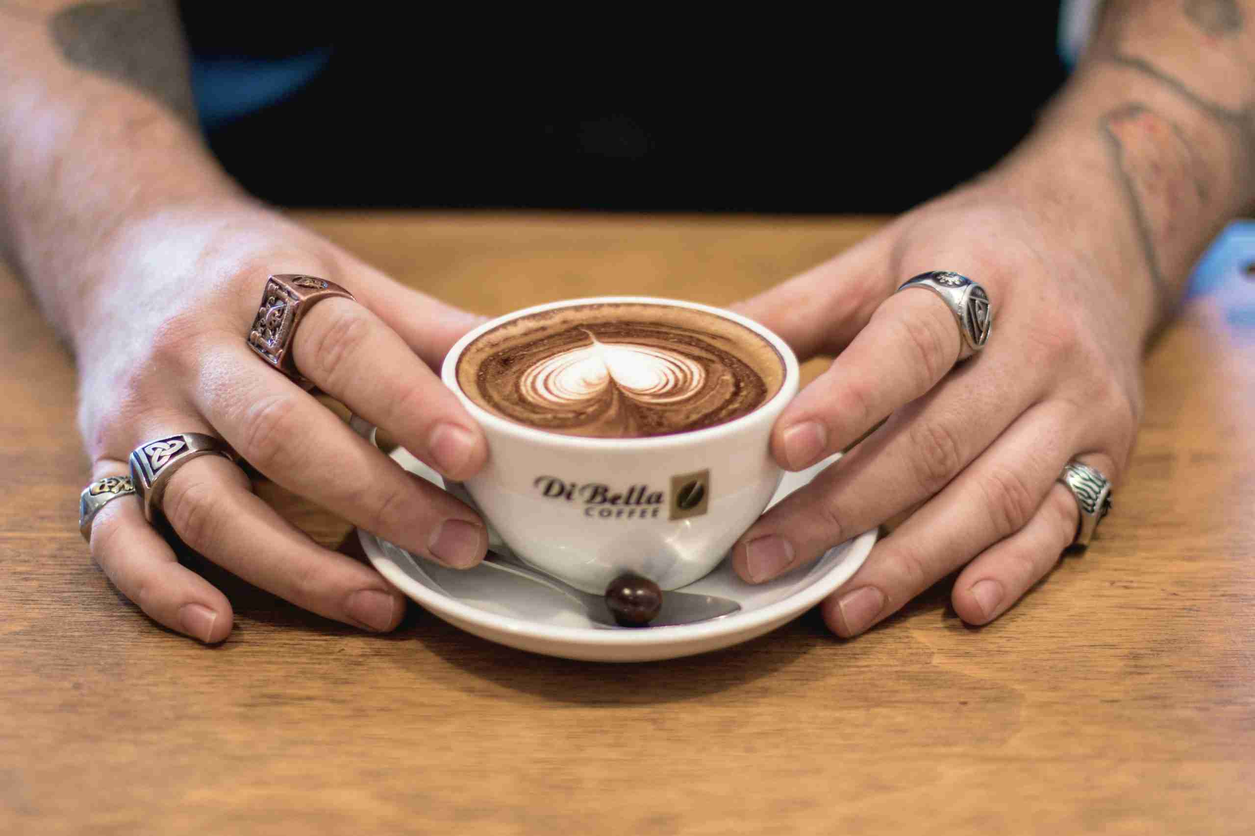 A photo of a coffee mug with a love heart shape made in the coffee.